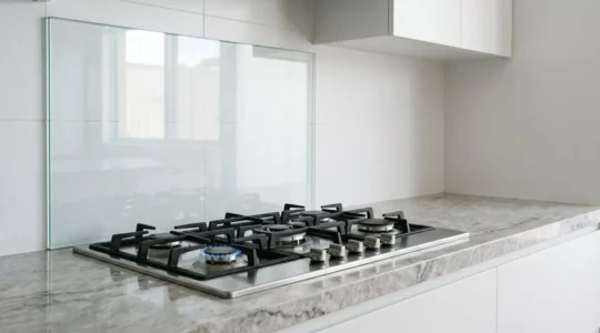 Crédence en verre trempé installée derrière une plaque de cuisson à gaz professionnelle dans une cuisine moderne